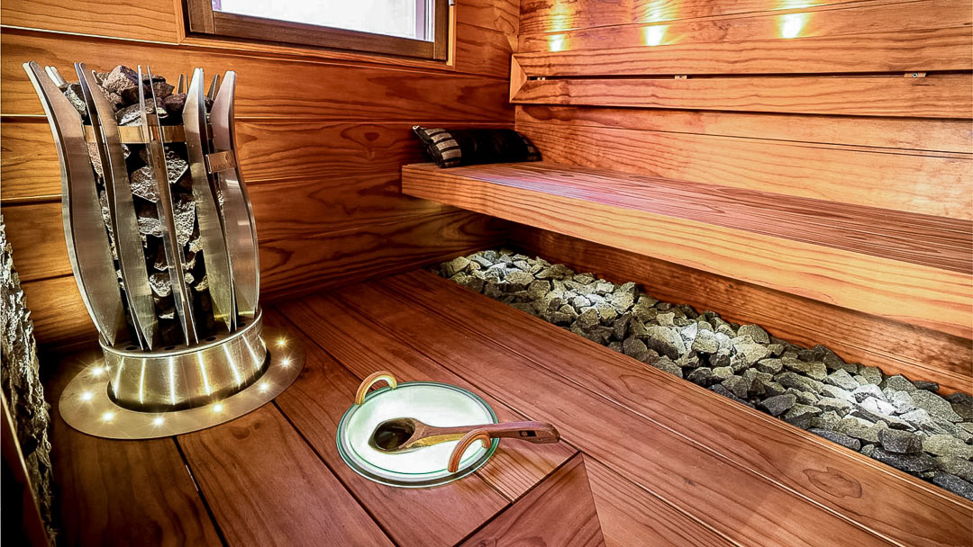 Recol Oy:n toteuttama moderni sauna puupaneeleilla. Saunassa on tyylikkäät puulauteet, design-kiuas ja tunnelmallinen valaistus. Kiukaan alla on kivet näkyvillä luoden luonnollisen ilmeen.