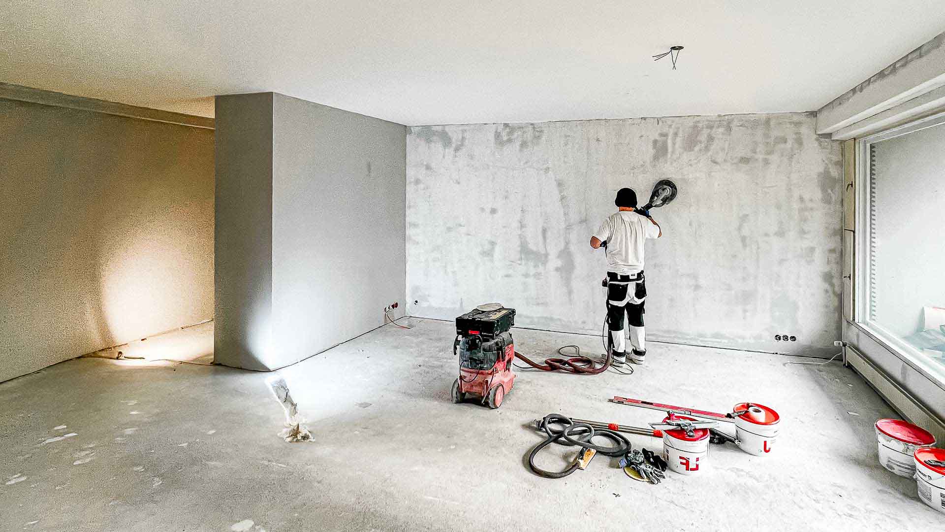 Recol Oy:n seinäremonttipalvelut. Kuvassa työntekijä viimeistelee seinäpintaa hiomakoneella. Laadukasta ja ammattitaitoista remontointia Uudenmaan alueella.